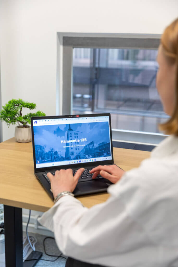 Woman using a laptop at a desk with a website on the screen, possibly for CRM solutions.
