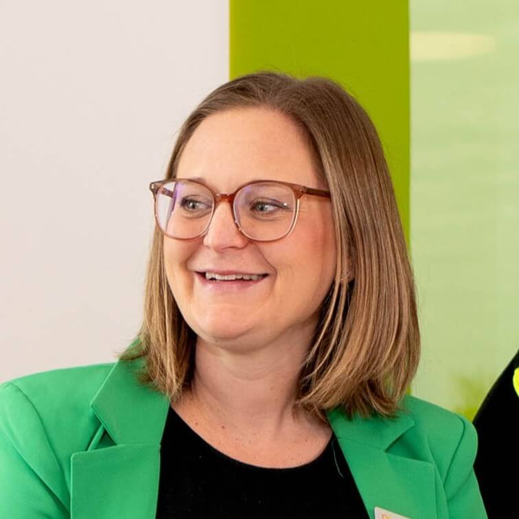 Smiling businesswoman with glasses and green blazer, representing professional CRM solutions.
