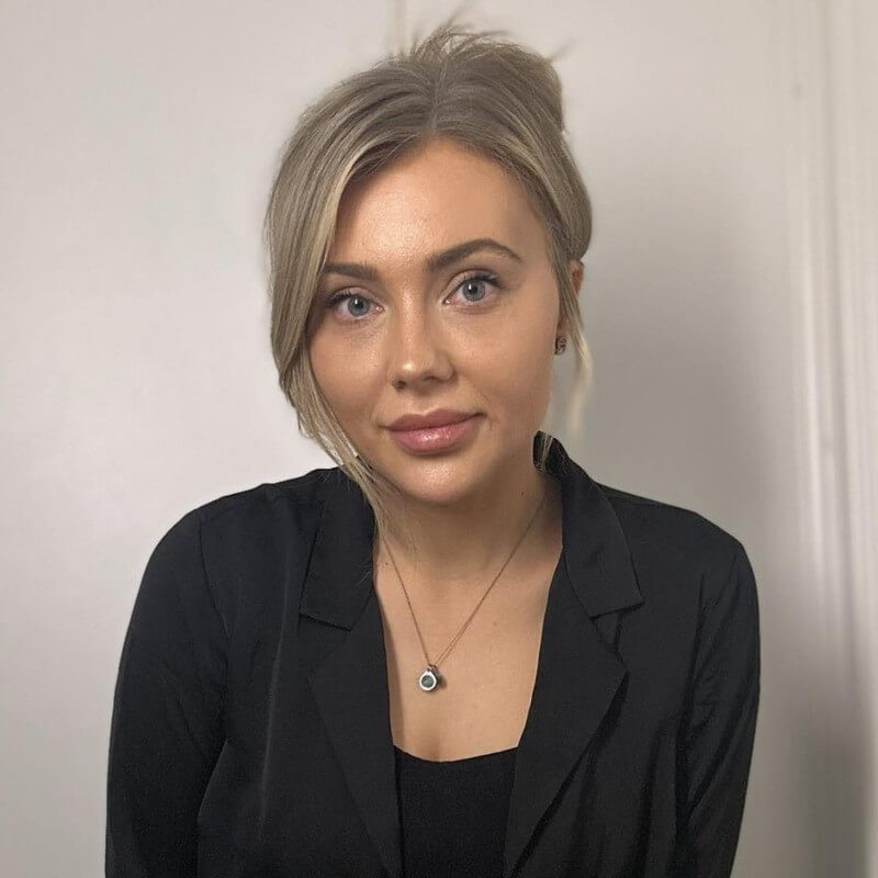 A woman with a professional demeanor, dressed in a black blazer, likely representing consultancy or business services.