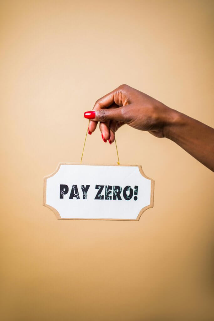 Hand holding a sign that reads 'PAY ZERO!' in bold black letters on a white background, implying zero payment or cost, which could relate to cost-saving solutions in CRM consultancy.