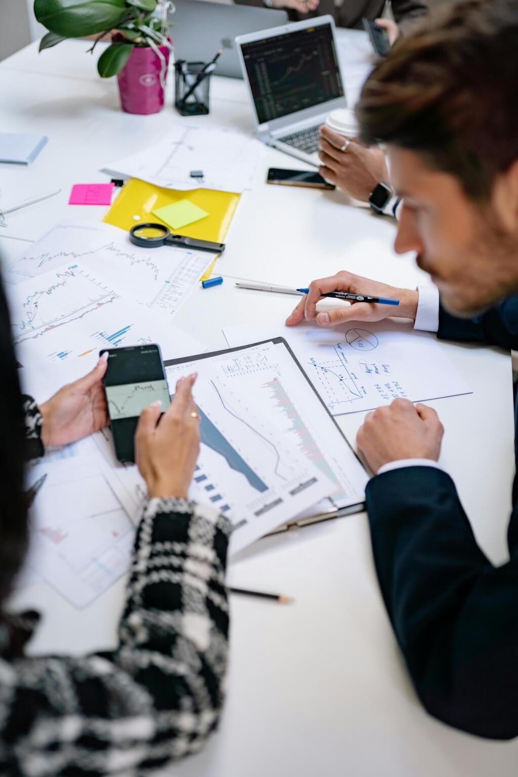 Two business professionals collaborating on documents and strategies, a meeting taking place at a working desk.