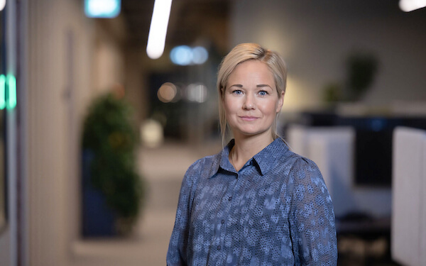 A confident woman standing in an office environment, professional setting for a CRM consultancy business