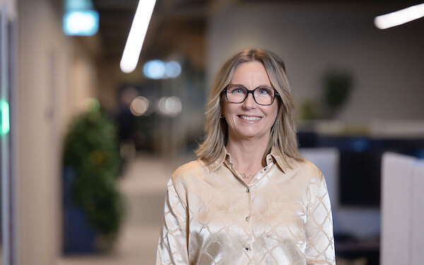Smiling businesswoman with glasses standing in an office.