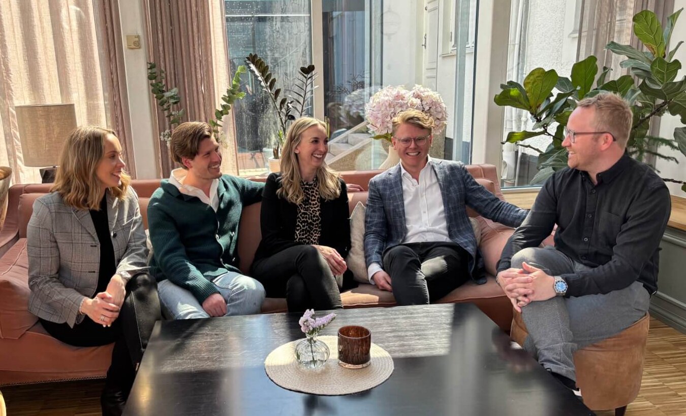 Group of business professionals engaged in a meeting or discussion in a modern office setting, sitting around a coffee table.