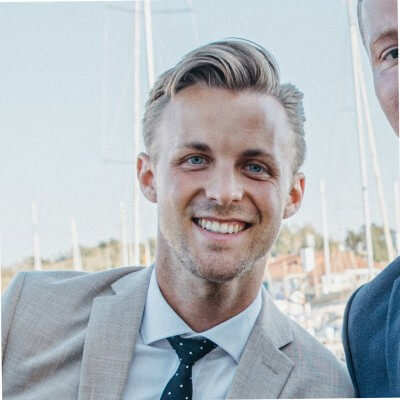 A smiling professional in a beige suit and patterned tie, portraying a friendly and approachable demeanor suitable for CRM consultancy or real estate solutions.