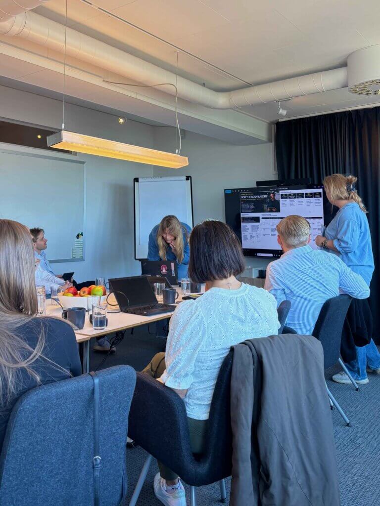 A professional CRM software training session in progress with consultants reviewing data on a shared large-screen display during a corporate consultation meeting.